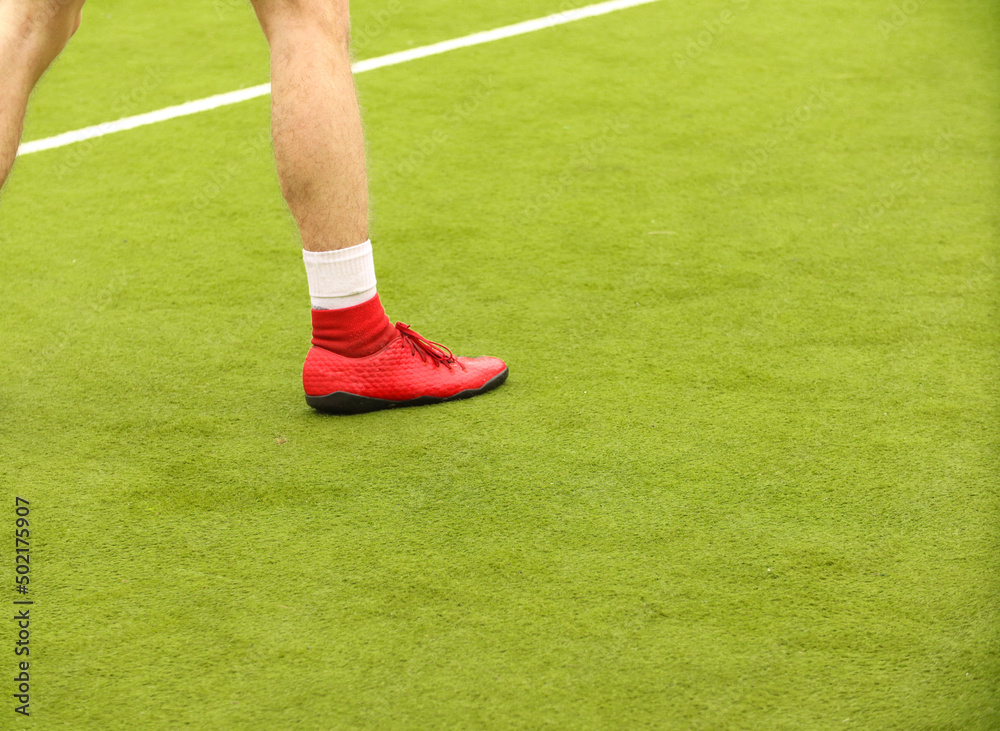 Obraz premium Players play mini football on the field. Legs, sneakers and a ball. Green football field.