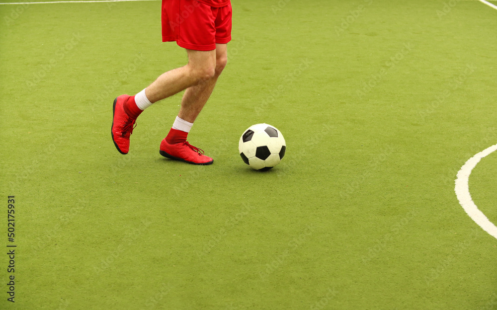 Players play mini football on the field. Legs, sneakers and a ball. Green football field. Players play mini football on the field. Legs, sneakers and a ball. Green football field.