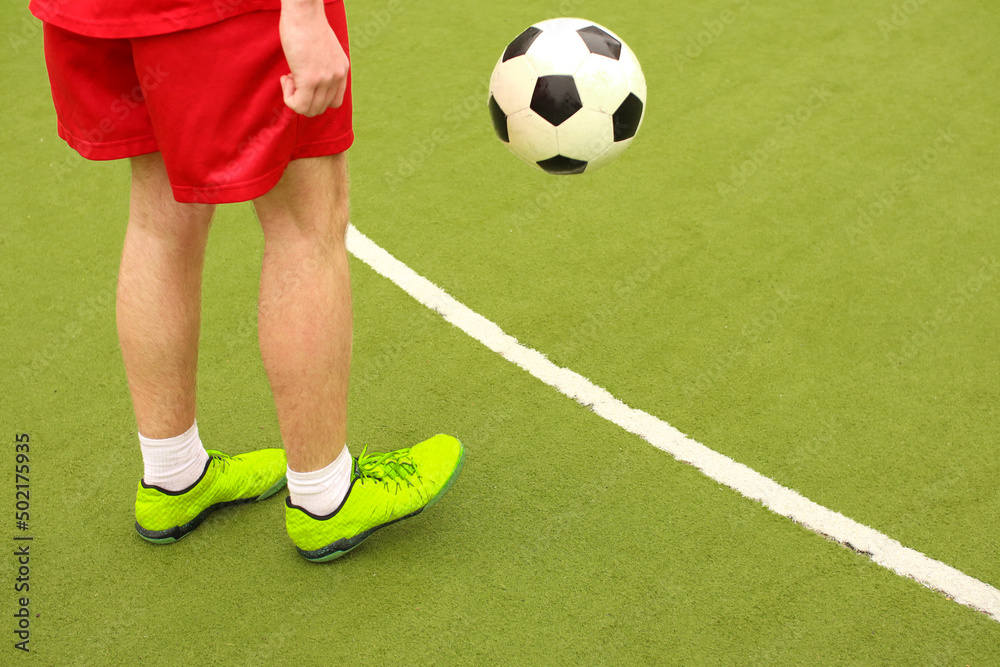 Fototapeta premium Players play mini football on the field. Legs, sneakers and a ball. Green football field.