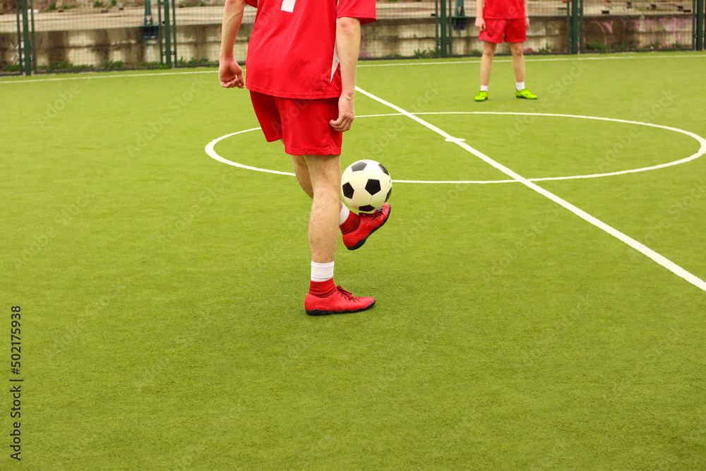 Players play mini football on the field. Legs, sneakers and a ball. Green football field. Players play mini football on the field. Legs, sneakers and a ball. Green football field.