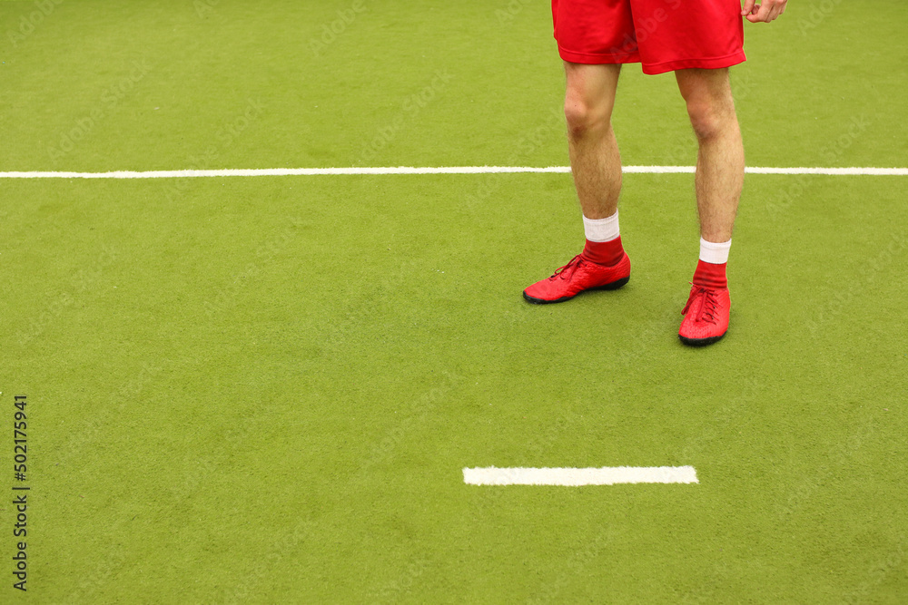 Players play mini football on the field. Legs, sneakers and a ball. Green football field. Players play mini football on the field. Legs, sneakers and a ball. Green football field.