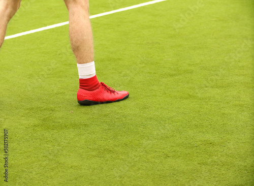 Players play mini football on the field. Legs, sneakers and a ball. Green football field.