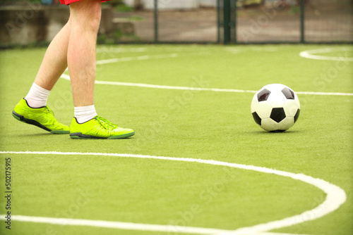 Fototapeta Naklejka Na Ścianę i Meble -  Players play mini football on the field. Legs, sneakers and a ball. Green football field.