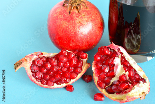 fresh pomegranate seeds with juice in glass on light blue background