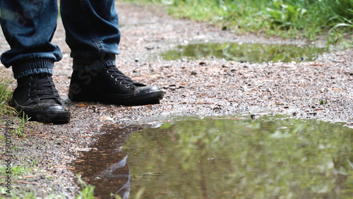 Close-up of man at puddle on forest path. Stock footage. View of feet of man standing at puddle and pondering how to go