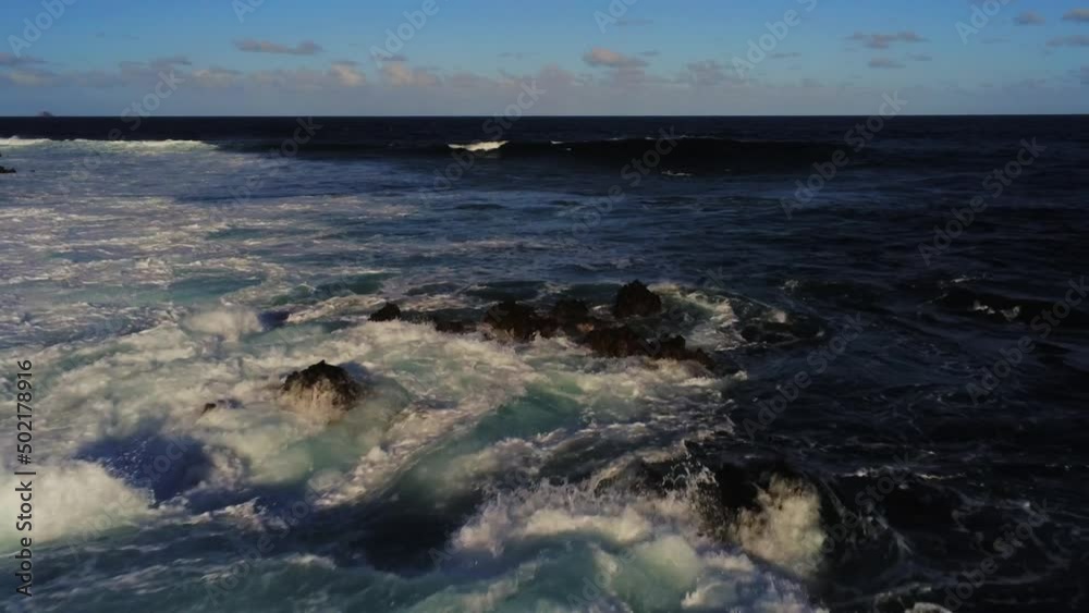 Shallow rocky coastline with ocean waves breaking and splashing, low altitude aerial view Shallow rocky coastline with ocean waves breaking and splashing, low altitude aerial view