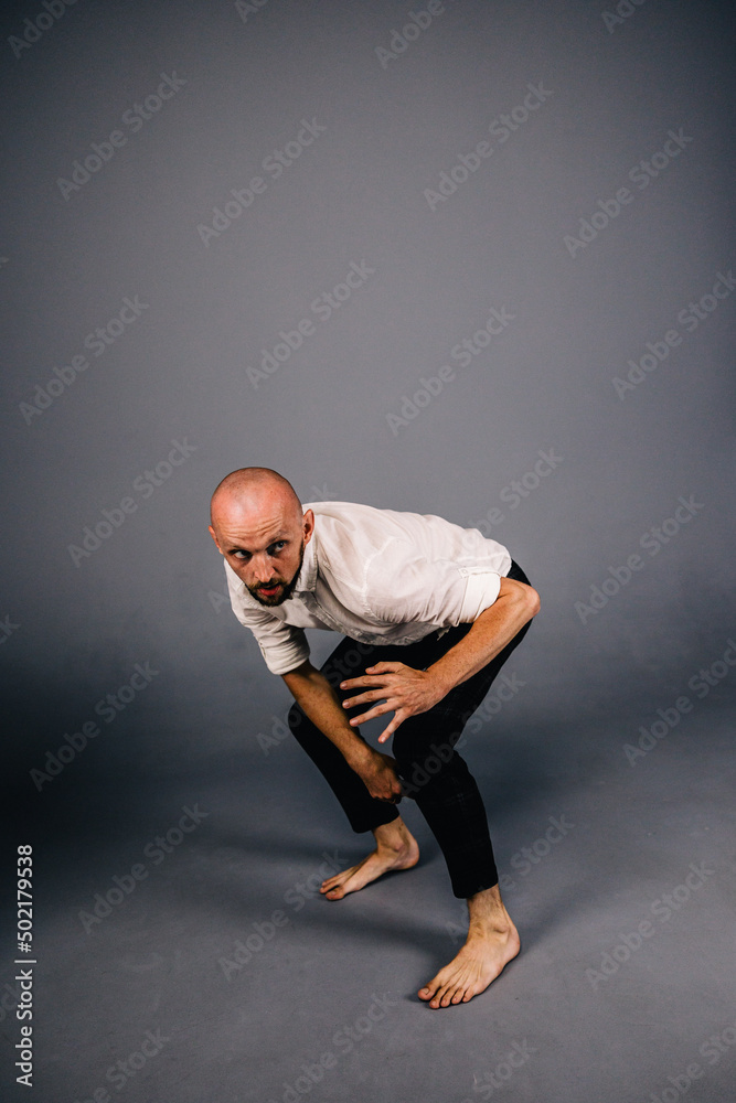 studio portrait of a bald guy with a beautiful beard barefoot in a white shirt and plaid pants dancing on a gray background studio portrait of a bald guy with a beautiful beard barefoot in a white shirt and plaid pants dancing on a gray background