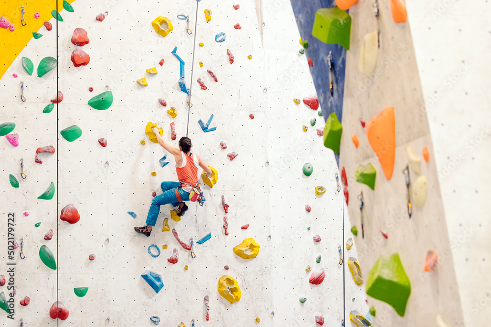 Young Woman rock climbing indoors.