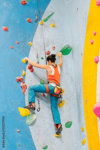 Young Woman rock climbing indoors.