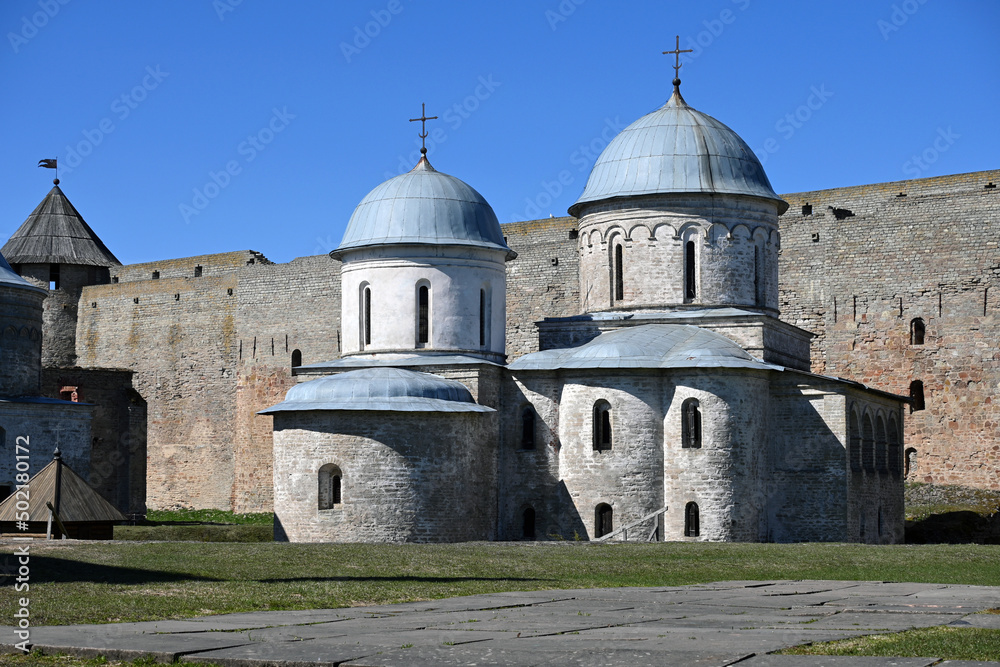 An ancient cathedral and church in the medieval fortress of Ivangorod on the border of Russia and Estonia in the Leningrad region against the background of the fortress wall. Medieval architecture and