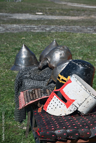 Stylized metal helmets of ancient Russian warriors and knights of the Livonia Order lie in a row on metal and leather armor. The historical heritage of Ancient Russia.  photo