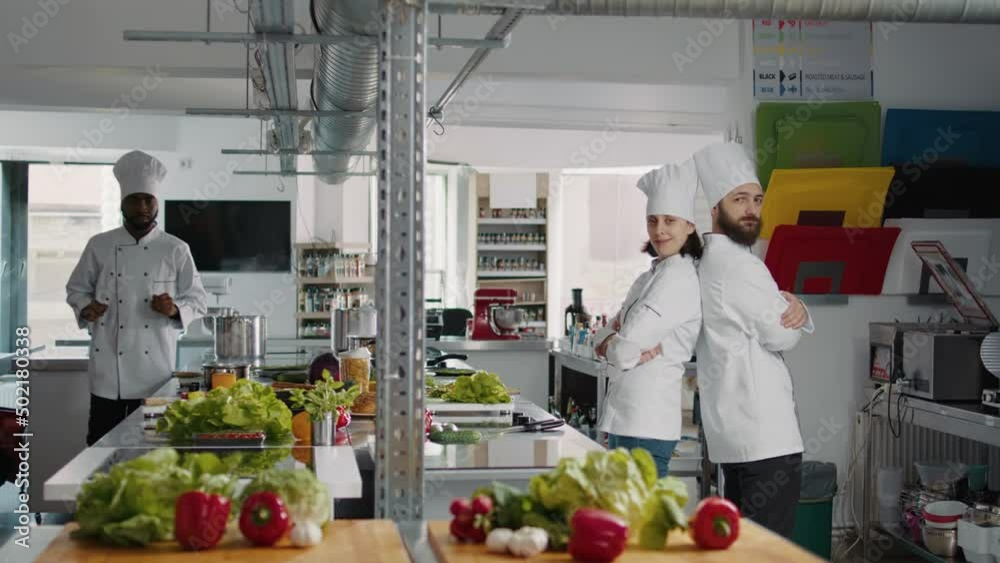 Portrait of professional chefs posing with arms crossed on camera, working in restaurant kitchen to make dish meal. Man and woman in uniform being professional cooks, preparing culinary recipe. Portrait of professional chefs posing with arms crossed on camera, working in restaurant kitchen to make dish meal. Man and woman in uniform being professional cooks, preparing culinary recipe.