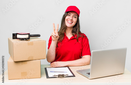 young pretty woman  smiling and looking friendly, showing number two. company packer employee photo