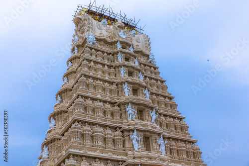 Temple tower or entrance of the 300 year old ancient and historic temple of goddess Chamundi with devotees at Chamundi Hill, Mysore. South Indian Style Temple Tower Vimana, Mysore, Karnataka, India photo