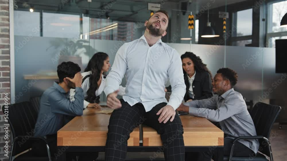 Chaotic co-workers in background arguing multiracial colleagues in boardroom young frustrated man worker pointing head making finger gun irritated tired employer sitting on table pretending headshot Chaotic co-workers in background arguing multiracial colleagues in boardroom young frustrated man worker pointing head making finger gun irritated tired employer sitting on table pretending headshot