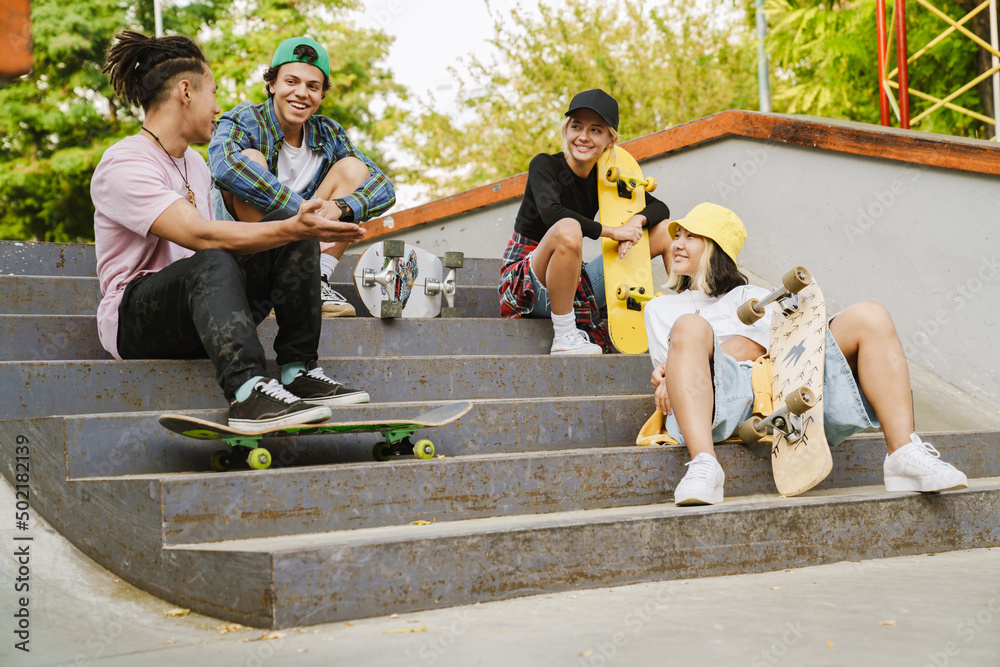 Multiracial teenagers talking while spending time at skate park