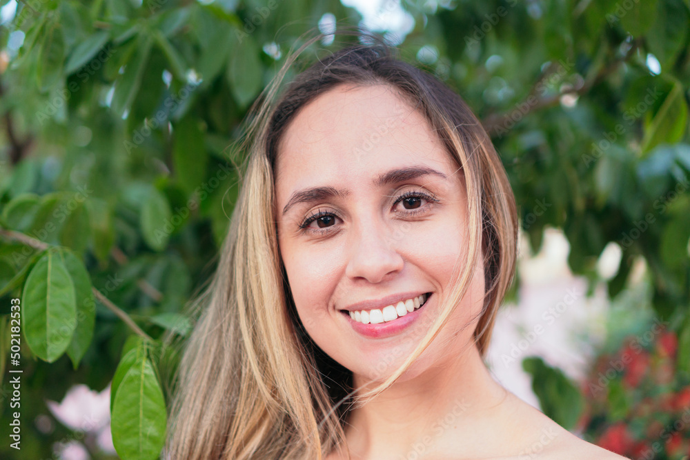 Latin Woman smiling and looking to the side while standing in an urban park. Latin Woman smiling and looking to the side while standing in an urban park.