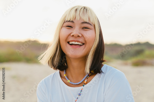 Fotografie Young asian woman laughing while walking on beach
