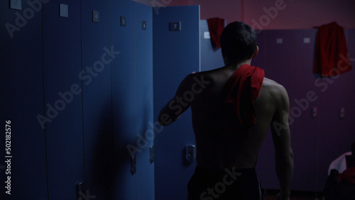 Quadro su tela Disappointed and tired sportsman in semi lit locker room