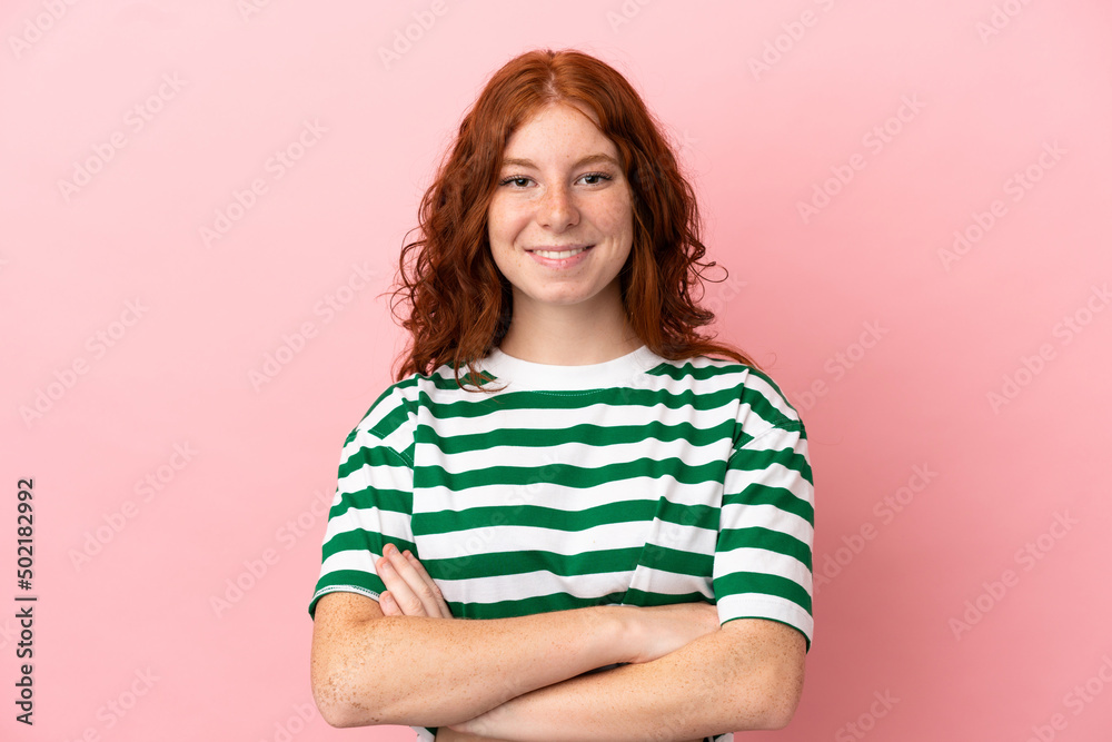 Teenager redhead girl over isolated pink background keeping the arms crossed in frontal position Teenager redhead girl over isolated pink background keeping the arms crossed in frontal position
