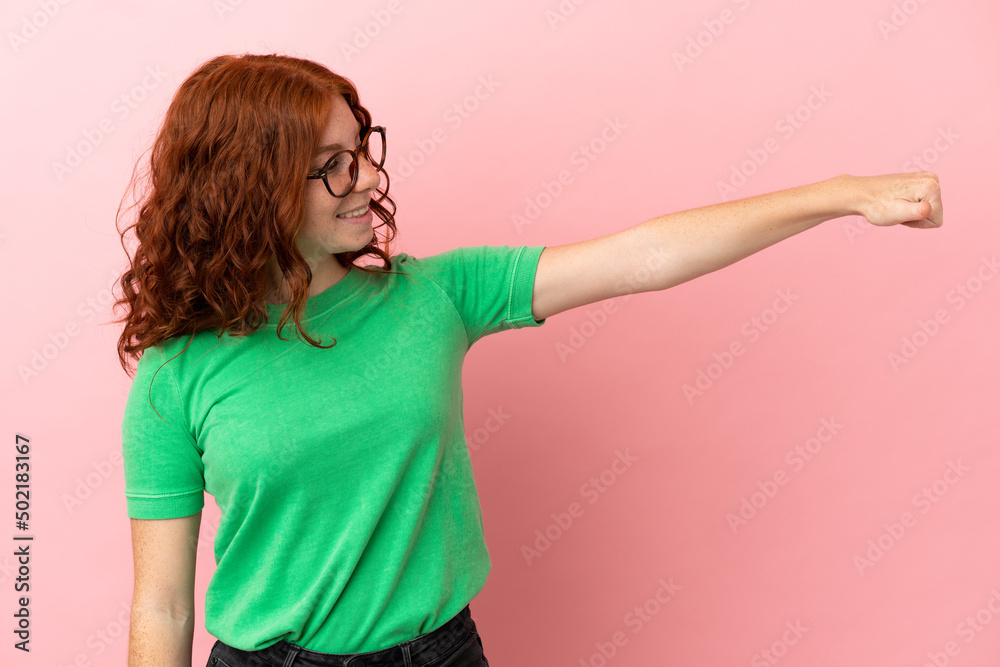 Teenager redhead girl over isolated pink background giving a thumbs up gesture