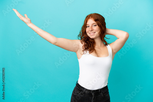 Teenager redhead girl isolated on blue background in swimsuit in summer holidays © luismolinero