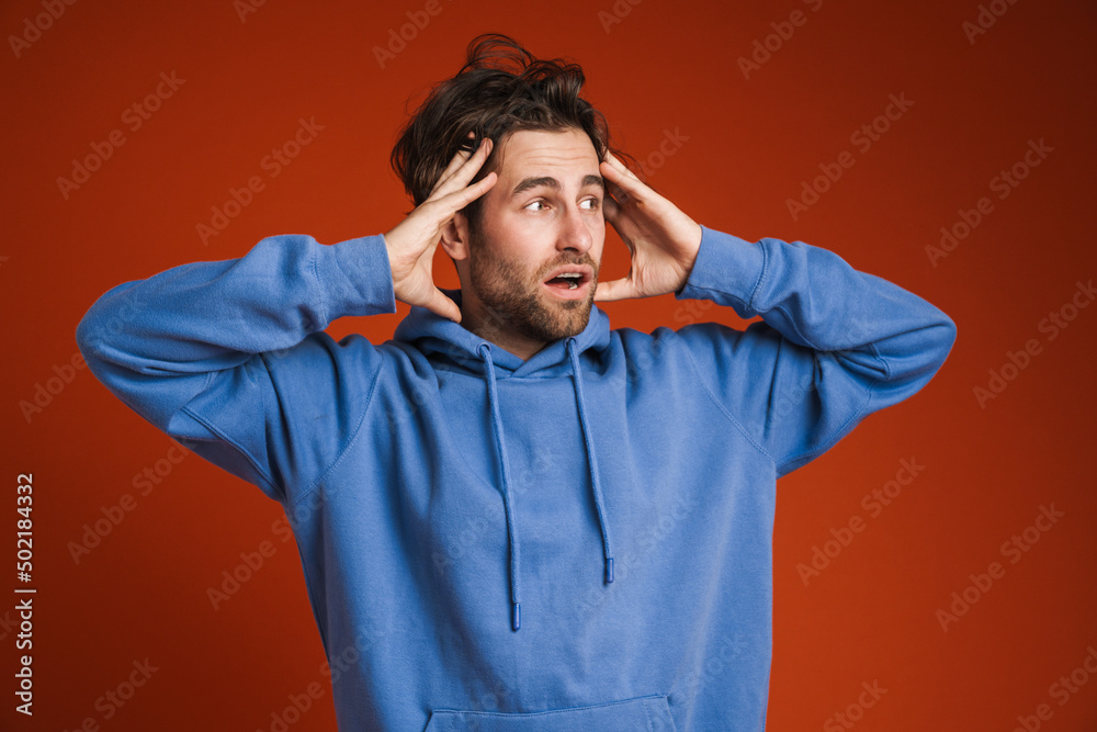 Young man holding his head while expressing surprise Young man holding his head while expressing surprise
