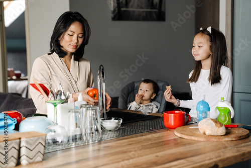Happy mother cooking while spending time with her children