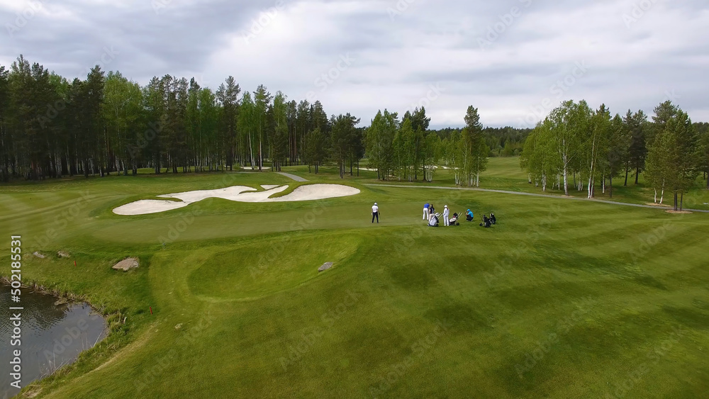 Obraz premium Golfers hitting golf shot with club on course while on summer vacation, aerial