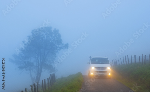 Car with lights on a foggy mountain road, mount Jaizkibel, Euskadi