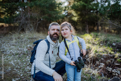 Father with small daughter with binoculars on walk in spring nature together.