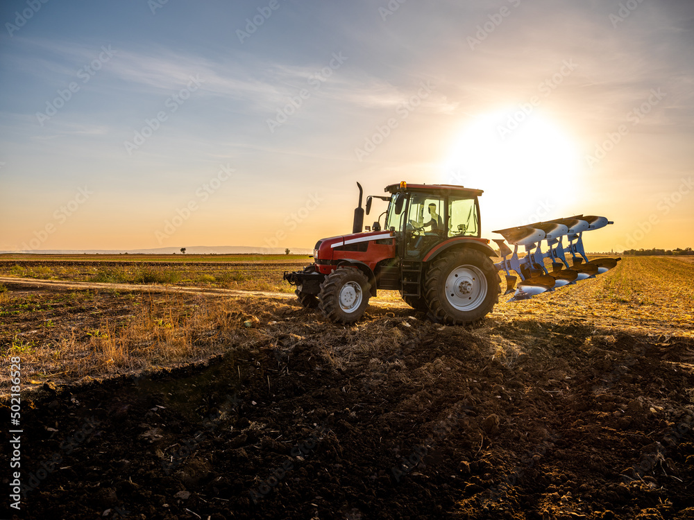 Farmer in tractor plowing preparing stubble field cultivating for seeding crops. Farmer in tractor plowing preparing stubble field cultivating for seeding crops.
