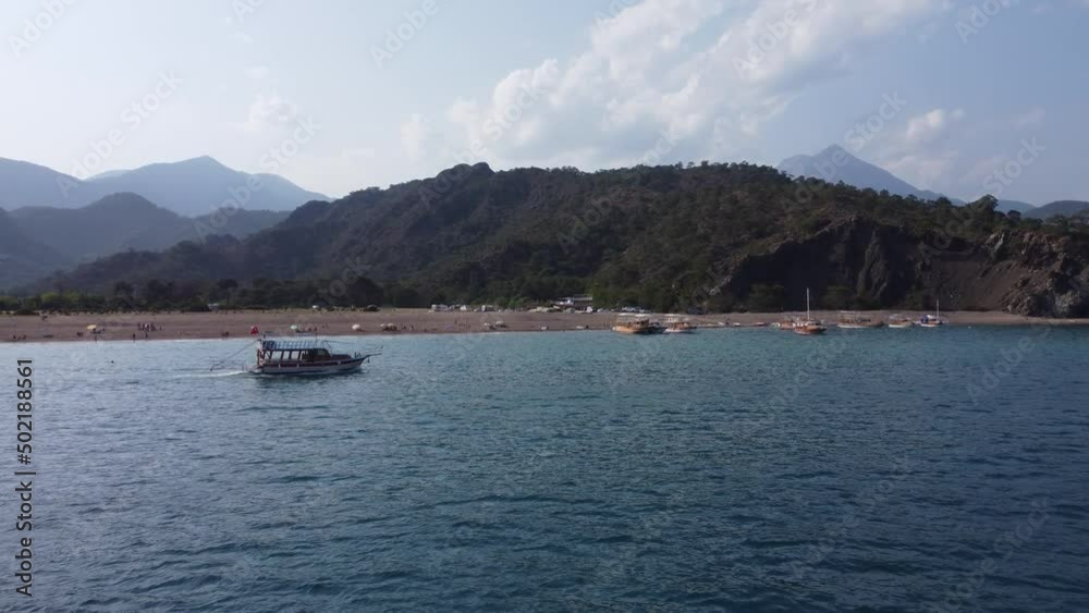 Aerial view, following a tourist boat, calm sea on a sunny day. Sightseeing motorboat in Antalya, mountain landscape. Boat with tourists sailing Antalya Turkey with clear turquoise water surrounded by Aerial view, following a tourist boat, calm sea on a sunny day. Sightseeing motorboat in Antalya, mountain landscape. Boat with tourists sailing Antalya Turkey with clear turquoise water surrounded by
