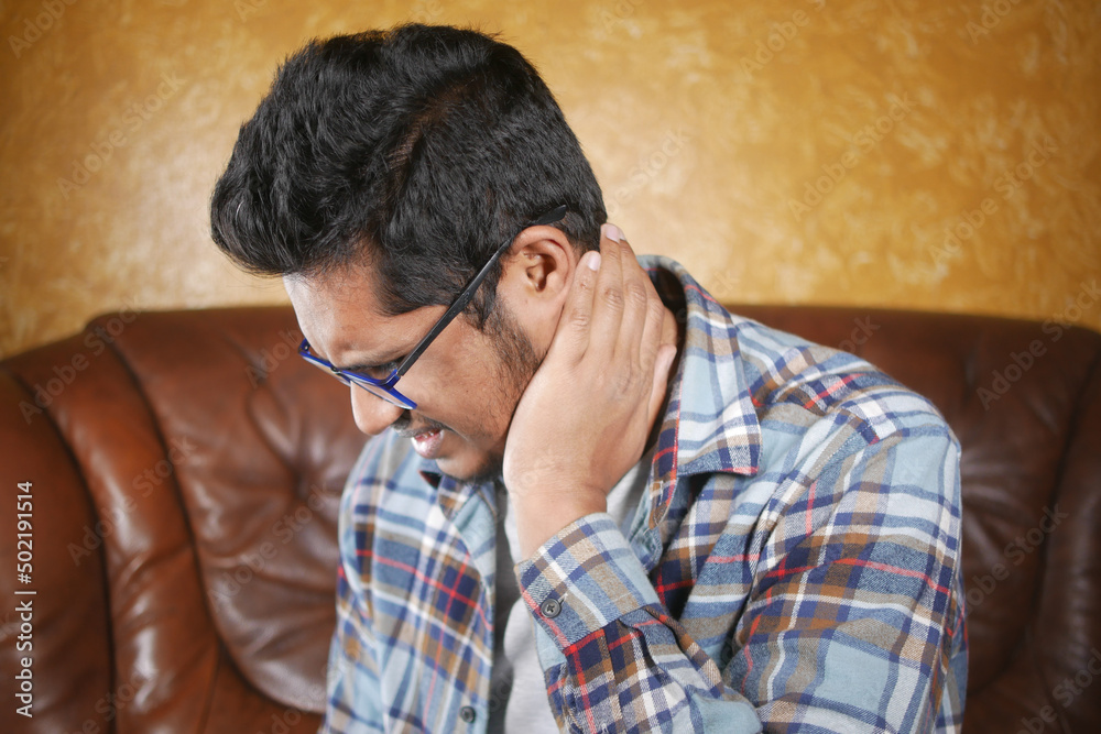 man suffering chronic neck pain while sitting on sofa man suffering chronic neck pain while sitting on sofa