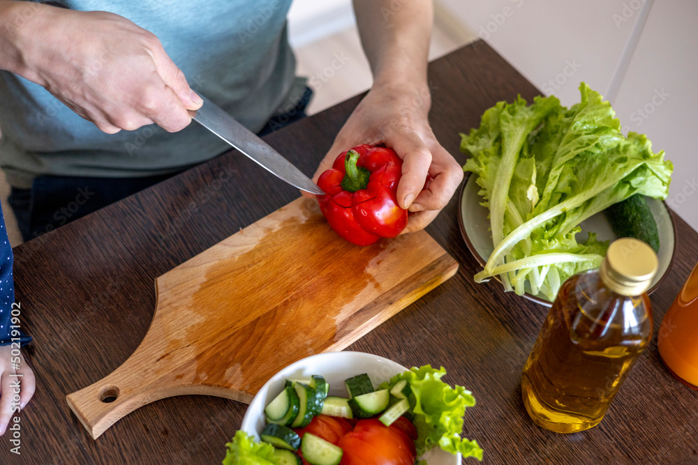 Man cuts vegetables in the kitchen to prepare a vegetarian dish. Family lifestyle Man cuts vegetables in the kitchen to prepare a vegetarian dish. Family lifestyle