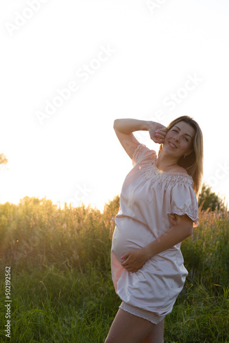 tender pregnancy portrait on sunset. expecting mother to be outside in pink dress. Beautiful tender mood photo of pregnancy.