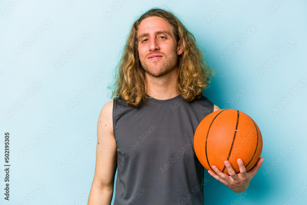 Young caucasian man playing basketball isolated on blue background happy, smiling and cheerful.