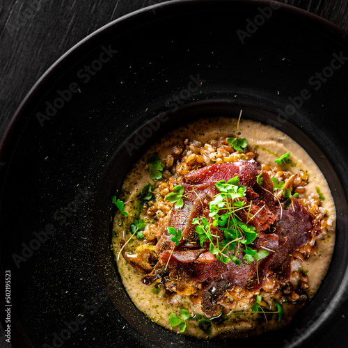 Spelt with venison jerked beef in black plate