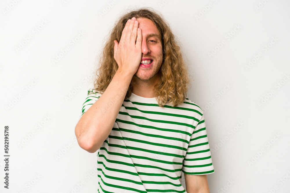 Fototapeta premium Young caucasian man isolated on white background having fun covering half of face with palm.