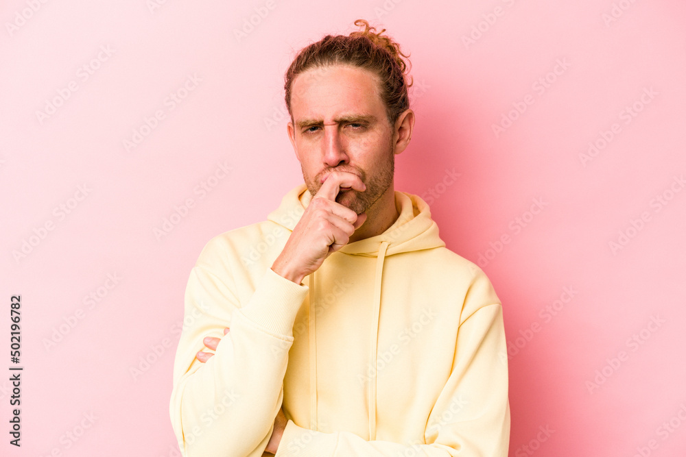 Young caucasian man isolated on pink background thinking and looking up, being reflective, contemplating, having a fantasy. Young caucasian man isolated on pink background thinking and looking up, being reflective, contemplating, having a fantasy.