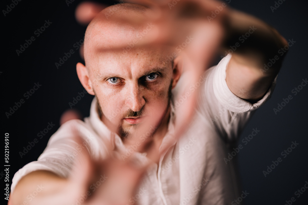 Studio portrait through the fingers of a bald man with a beautiful beard on a black background Studio portrait through the fingers of a bald man with a beautiful beard on a black background