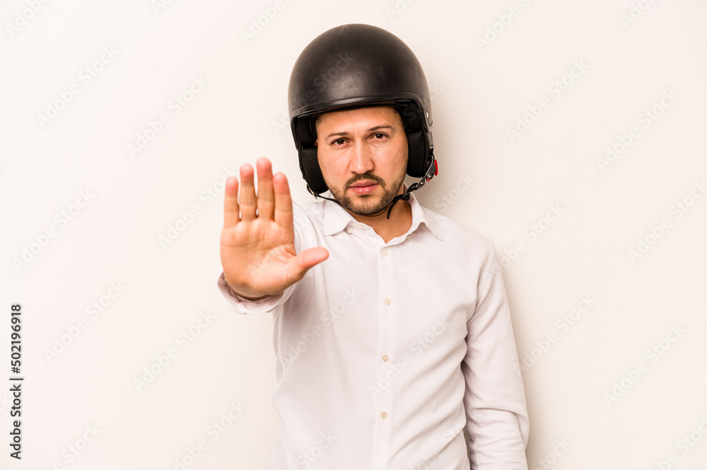 Hispanic business man going to work with motorcycle isolated on white background standing with outstretched hand showing stop sign, preventing you. Hispanic business man going to work with motorcycle isolated on white background standing with outstretched hand showing stop sign, preventing you.