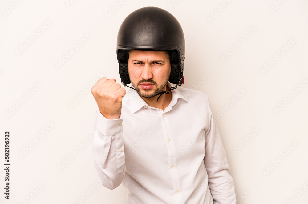 Hispanic business man going to work with motorcycle isolated on white background showing fist to camera, aggressive facial expression. Hispanic business man going to work with motorcycle isolated on white background showing fist to camera, aggressive facial expression.