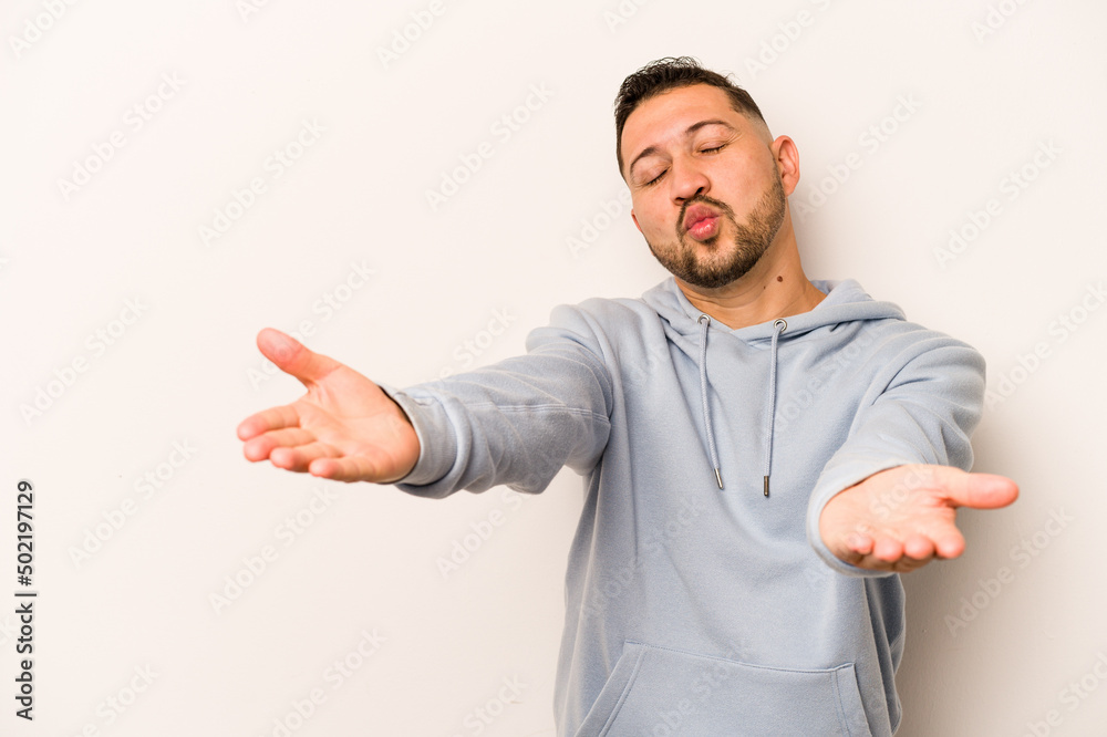 Young hispanic man isolated on white background folding lips and holding palms to send air kiss. Young hispanic man isolated on white background folding lips and holding palms to send air kiss.