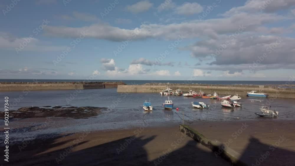 Fishing boats at low tide and the harbour in Staithes, Yorkshire. Pan left Fishing boats at low tide and the harbour in Staithes, Yorkshire. Pan left