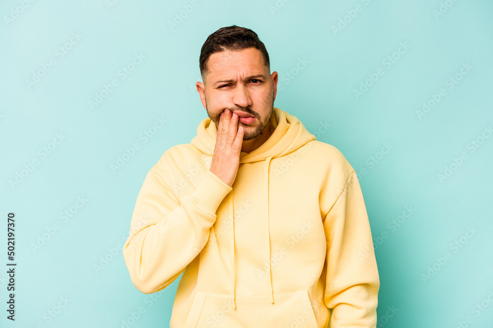 Young hispanic man isolated on blue background having a strong teeth pain, molar ache.