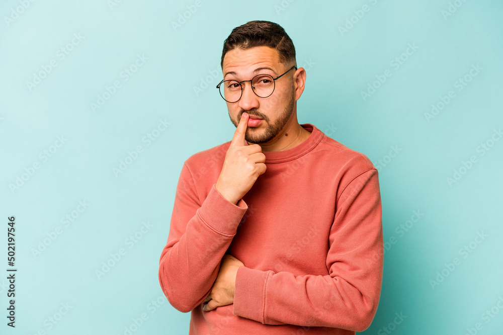 Young hispanic man isolated on blue background thinking and looking up, being reflective, contemplating, having a fantasy. Young hispanic man isolated on blue background thinking and looking up, being reflective, contemplating, having a fantasy.