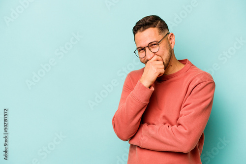 Young hispanic man isolated on blue background laughing happy, carefree, natural emotion.