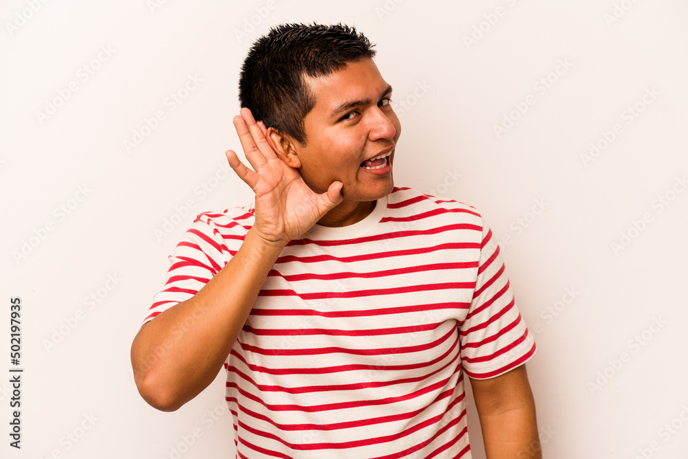 Young hispanic man isolated on white background trying to listening a gossip. Young hispanic man isolated on white background trying to listening a gossip.