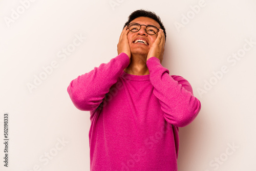 Young hispanic man isolated on white background laughs joyfully keeping hands on head. Happiness concept.